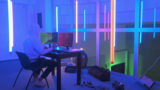 黑客工作地点黑客在一个有彩色荧光灯的房间工作视频
