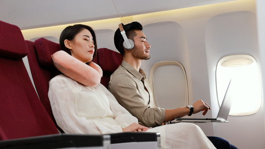 机舱里男乘客带耳机听音乐视频