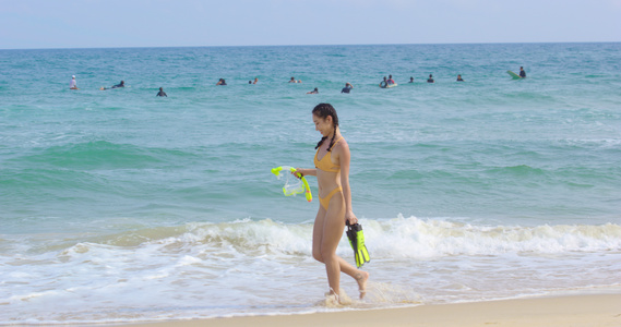 8K海边女性拿着潜水装备走在沙滩上视频