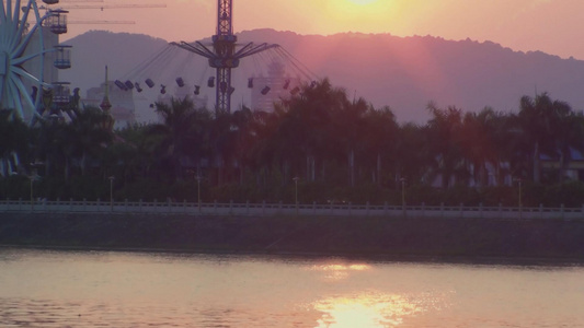 4k夕阳黄昏倒影波光粼粼的湖面游乐场视频