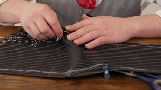 面目全非的男人裁缝手用涂油缝缝制了一件高级英式面料夹克。这个剪裁过程是在深灰色/黑色细条纹羊毛西装布上完成的视频