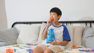 小男孩在沙发上看电视吃零食47秒视频