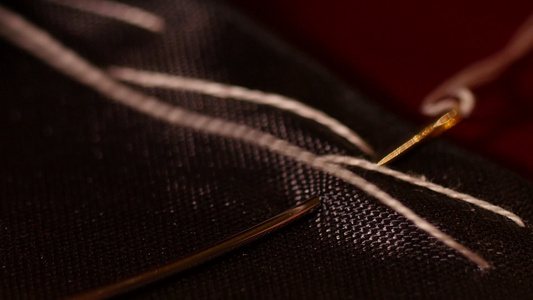 男裁缝手缝黑色线与白色疏缝线的宏观照片。缝线是用机器或手工缝制长的、易于拆卸的运行针迹。它也被称为钉钉视频