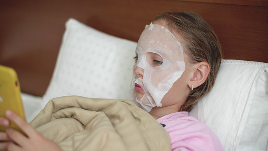 皮肤上戴着布化妆品面具的年轻女孩躺在坏处十几岁的女孩视频