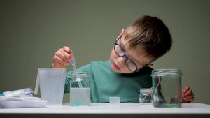 可爱的男孩在学生桌的化学实验室使用移液器在家上学做21秒视频