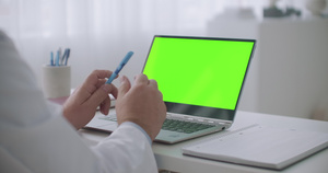 医生面对着绿色屏幕的笔记本电脑12秒视频