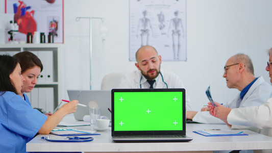 一组医生在镜头前使用带绿色屏幕的笔记本电脑视频