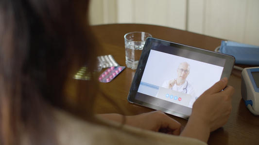执业医生通过平板电脑屏幕上的视频会议患者医生通过平板视频