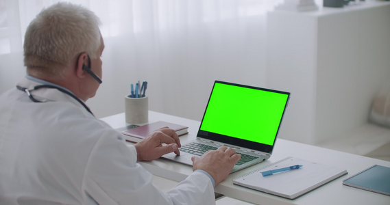 经验丰富的医生正在通过笔记本电脑上的视频通话聆听患者视频