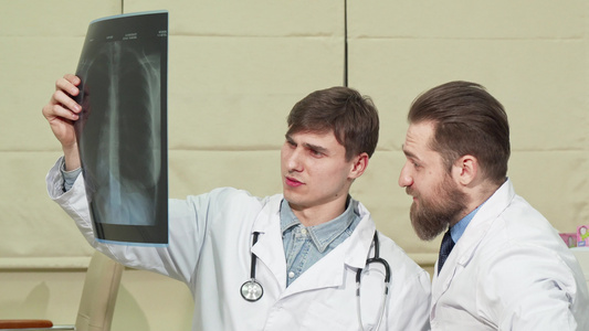 两名男性医生检查一名病人的肺X光视频