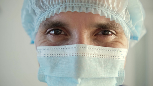 一名男性医生在大流行病期间戴着保护面罩疲倦的医生通过视频