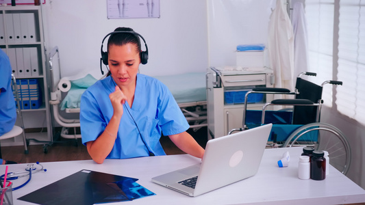在医院使用耳机的外科医生助理在医院接听病人电话视频