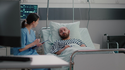 与氧气管一起坐在床上的生病男子向医疗护士解释病症症状视频