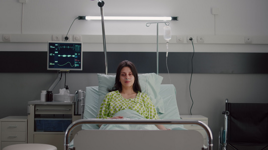 病人穿着鼻氧氧管看着躺在床上的摄像头视频