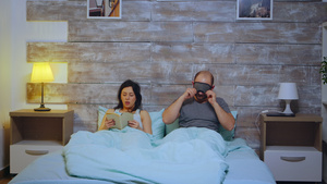 妇女读一本在卧室里穿着睡衣的书而丈夫用睡眠面具蒙住14秒视频