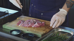 一名厨师在煮牛排前给猪肉加盐9秒视频