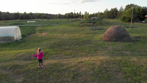 日落时身穿粉红连帽帽的女童在干草堆附近运行和发射滑翔机6秒视频