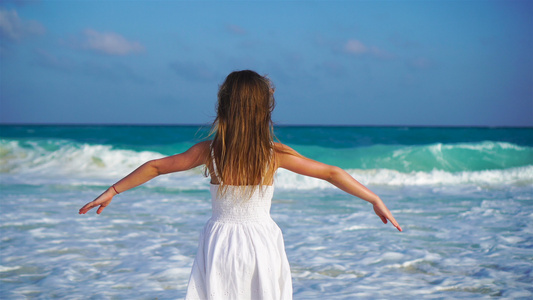 可爱的快乐小女孩在白色的沙滩上看着大海嘈杂的大海和视频