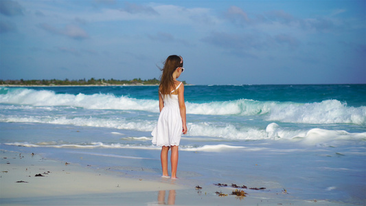 可爱的快乐小女孩在白色的沙滩上看着大海嘈杂的大海和视频