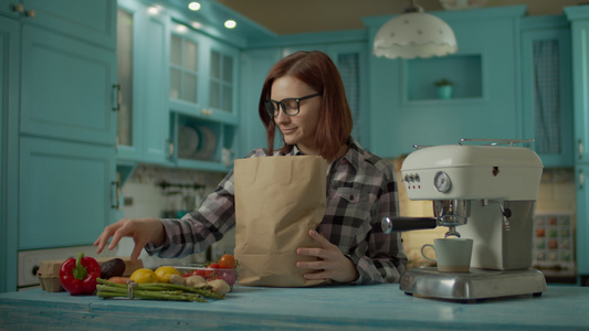 戴眼镜的年轻成年女性拿着纸袋里面装着新鲜的食物在家里视频