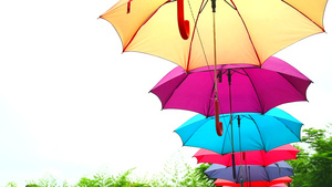 色彩多彩的伞式雨伞线装饰户外在蓝色天空白云上风向移动11秒视频