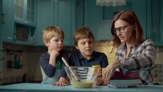 30多岁的年轻母亲带着两个孩子在家里的蓝色厨房里用华夫视频