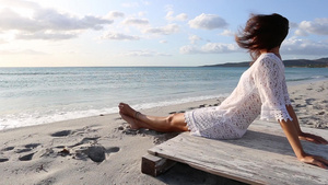 年轻女性坐在海边在黎明风中看着地平线54秒视频