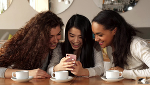 三个女孩在咖啡厅的智能手机上观看一些东西12秒视频