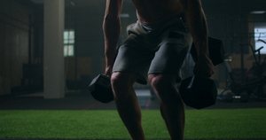 一个强壮的男人手里拿着哑铃在健身房做弯腰30秒视频