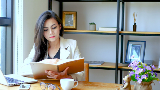 4K镜头美丽的亚洲女商人坐在电脑笔记本电脑前早上在视频