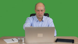 商人在绿色背景的办公室用笔记本电脑工作16秒视频