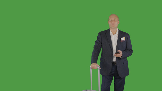 商人带着旅行手提箱拿着手机在绿色背景视频
