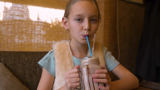 喝奶昔鸡尾酒的十几岁女孩在咖啡厅的餐桌上视频