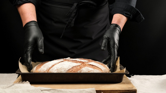 戴着黑色乳胶手套的厨师拿着烤盘上面放着烤黑麦面包黑色视频