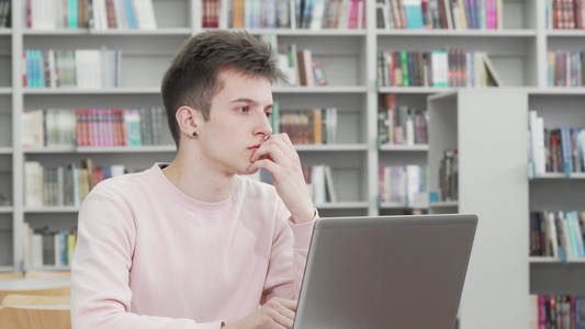 年轻人在图书馆做笔记本电脑工作时看着体贴的年轻男子视频