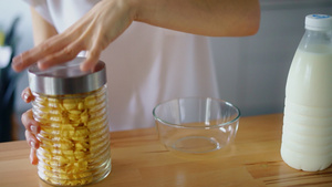 妇女把手打开罐子将玉米片倒入玻璃碗19秒视频