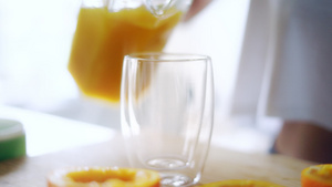 妇女把橙汁从玻璃罐倒到杯中14秒视频