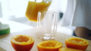 将新鲜橙汁从玻璃罐倒入杯中挤压橙汁15秒视频