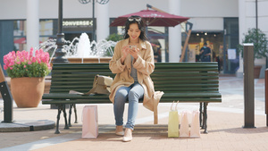 4k购物女性坐在长椅上休息使用手机9秒视频