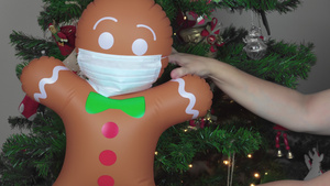 大的可充气姜饼人与口罩作为装饰挂在圣诞节树上24秒视频