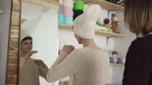 微笑的女人穿戴编织的帽子在展厅照镜11秒视频