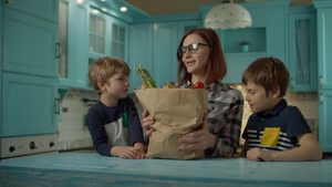 两个孩子帮助30多岁的年轻母亲打开装新鲜食物的纸袋27秒视频