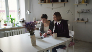 两名有创意的女士坐在桌上用笔记本在网上购物8秒视频