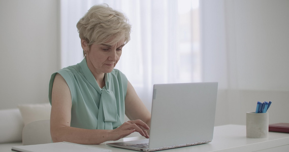 老年妇女在远程工作使用笔记本电脑与互联网连接进行通信视频