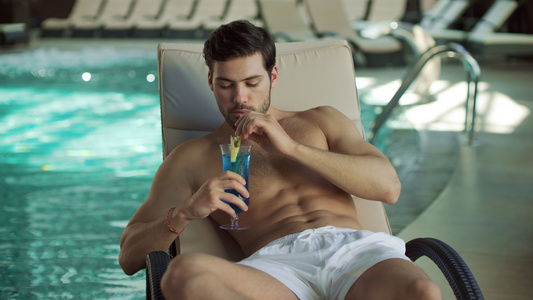 在现代游泳池喝鸡尾酒的男子视频