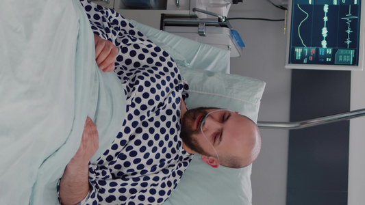 垂直视频躺在床上的病男子身着氧气管卧床解释疾病症状【竖版】视频
