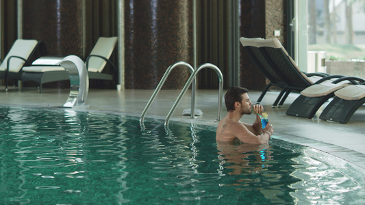 有魅力的男人在豪华游泳池喝鸡尾酒男的喝放松视频