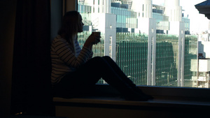 妇女在窗台上喝咖啡在窗户上看到城市风景23秒视频