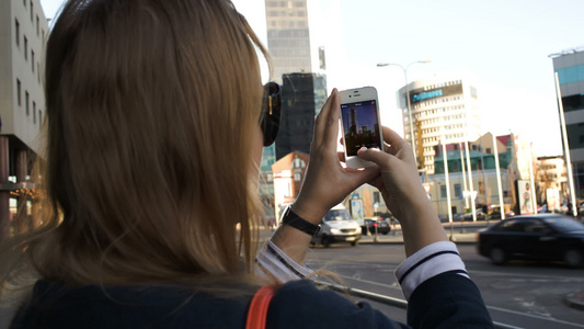 城市里的女人用她的智能手机拍照片视频