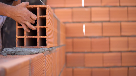 砖匠在建筑工地铺砖砖以形成建筑墙壁视频